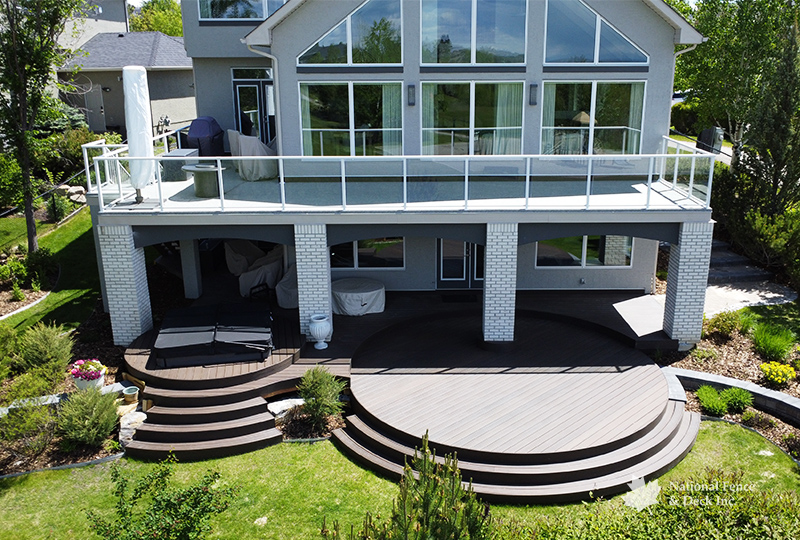 Walkout DekSmart vinyl deck with glass railing, and a curved Trex Transcend Spiced Rum lower deck.